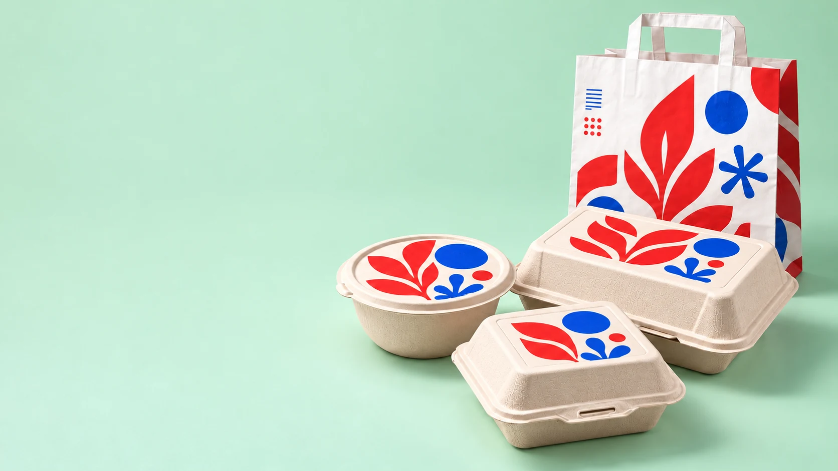 Envases de bagazo de caña con diseños botánicos solo en la parte superior de las tapas, junto a una bolsa de papel de delivery sobre fondo menta